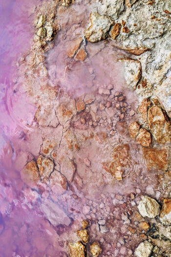 Full frame shot of pink salt lake and multi colored rocks