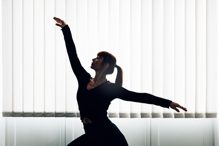 Professional dancer performing in studio under a big window.