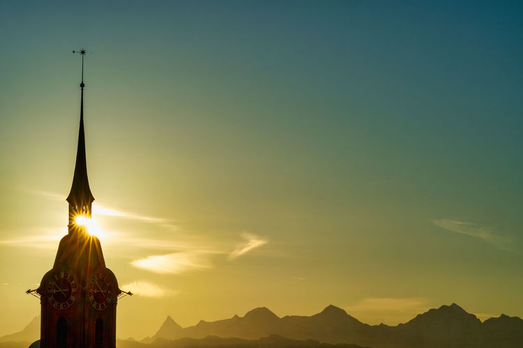 Statue by building against sky during sunset