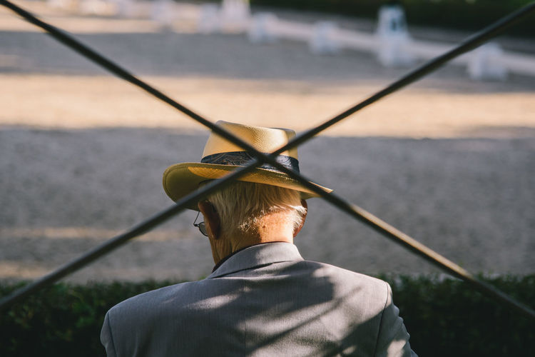 Rear view of man seen through metallic fence
