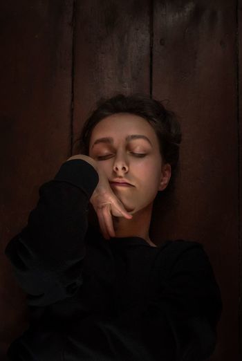 Portrait of young woman with eyes closed lying on floor