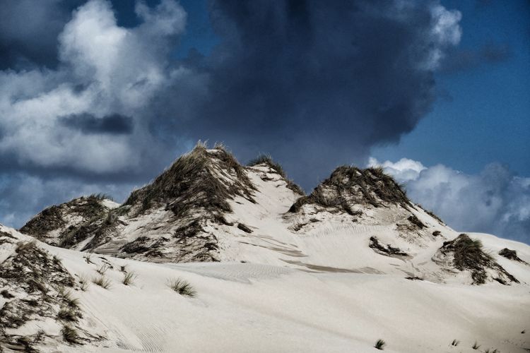 Scenic view of sand dune against dramatic sky