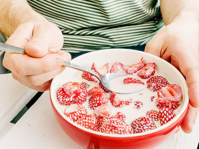 Man enjoying strawberries with milk, an old swedish midsummer tradition