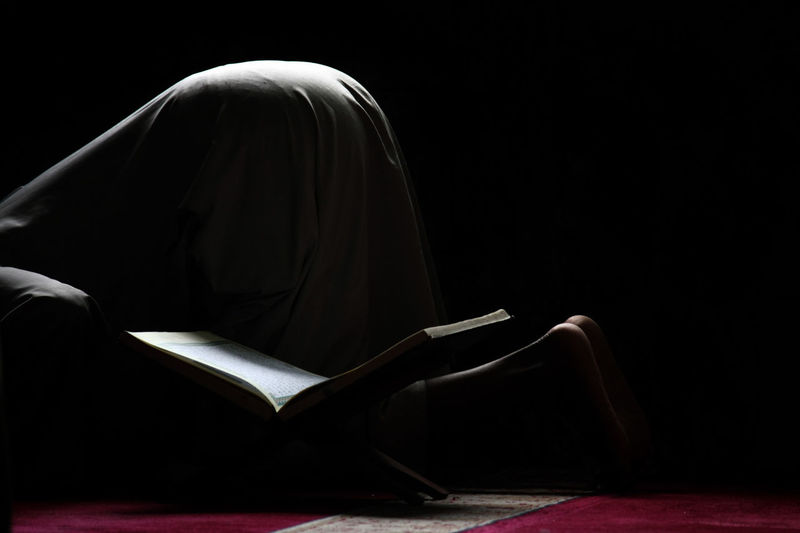 Low section of man praying by koran at home