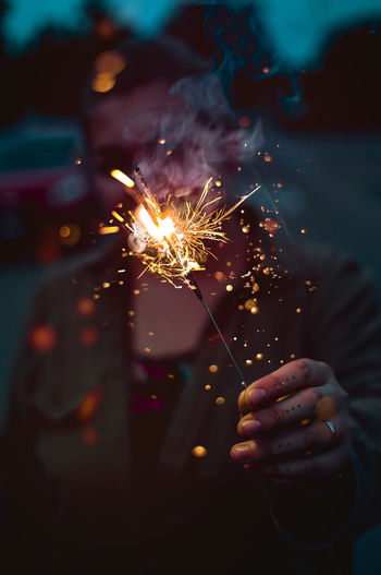 Close-up of man holding sparkler at night