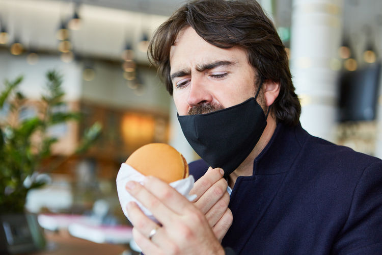 Close-up of man holding hamburger outdoors