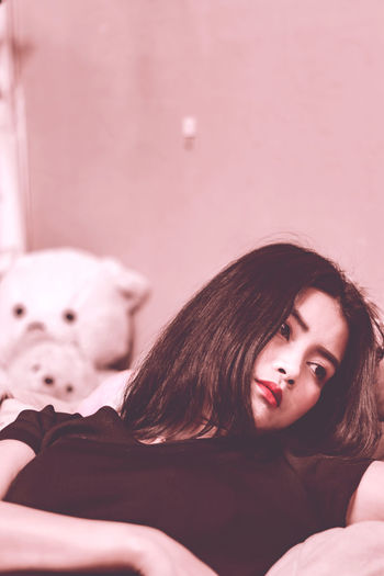 Portrait of young woman lying down on bed at home