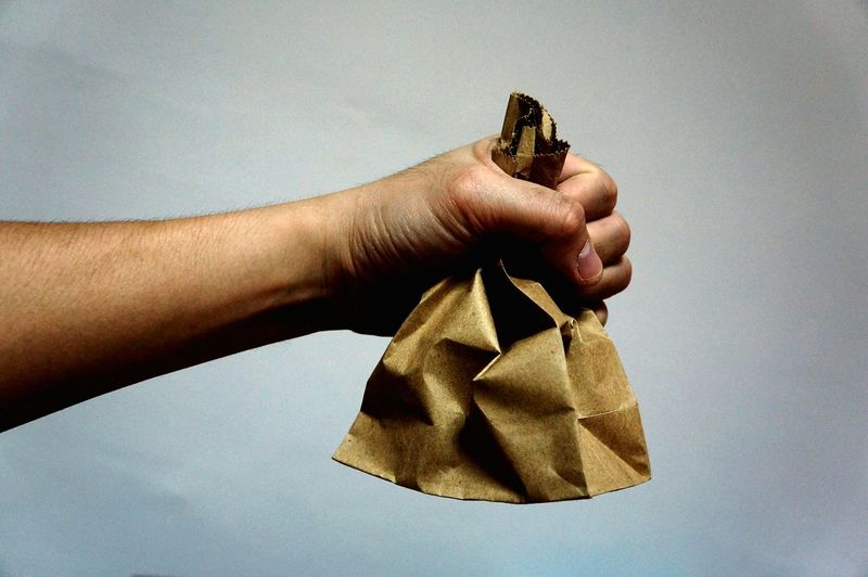 Close-up of cropped hand holding brown paper bag