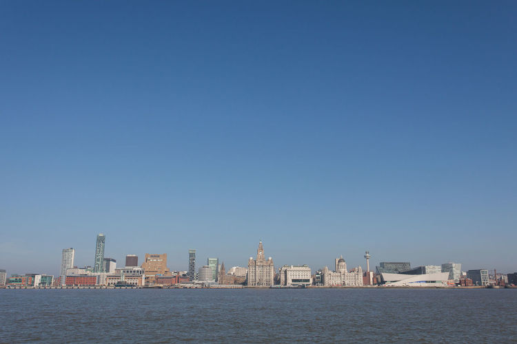 City in front of sea against clear sky