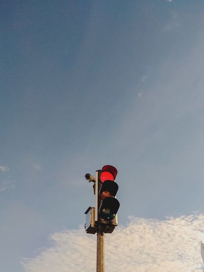 Low angle view of street light against sky with red light on