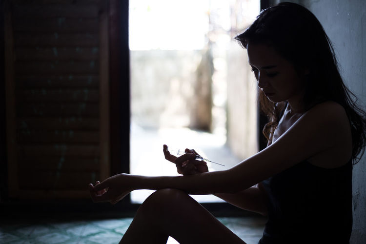 Side view of woman injecting on hand with syringe