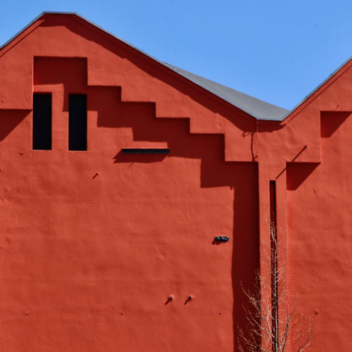 Low angle view of unusual red building against clear sky