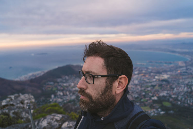 Close-up of man looking away against cloudy sky