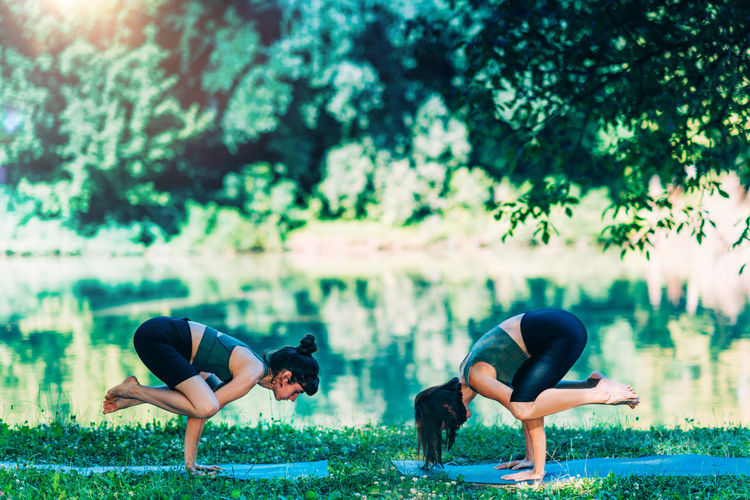 Women doing yoga by the water. crane- crow standing arm