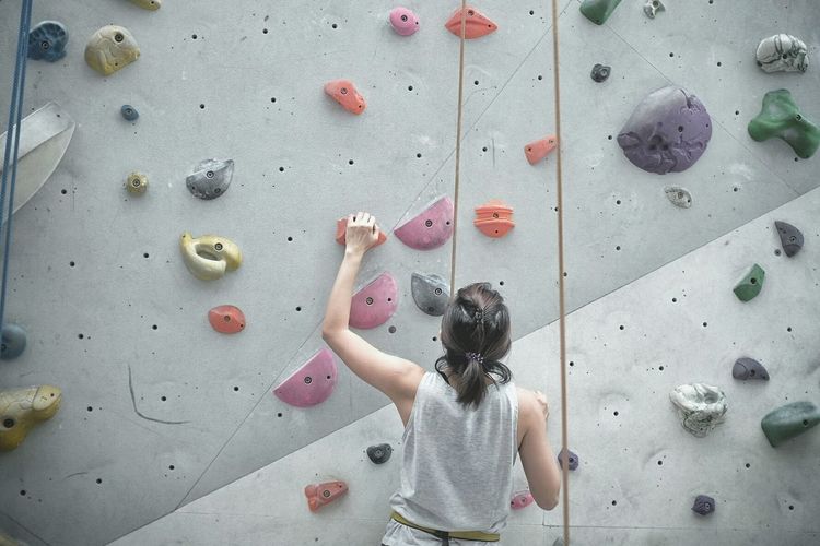 Rear view of woman climbing on wall