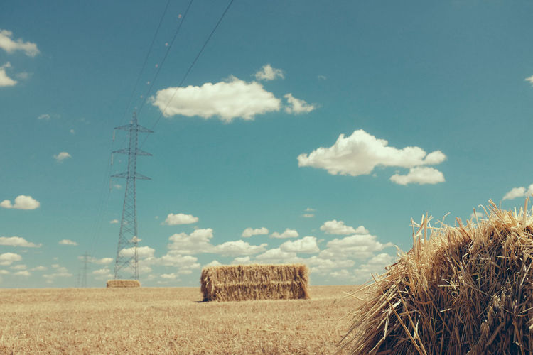 Hay bales on field against sky