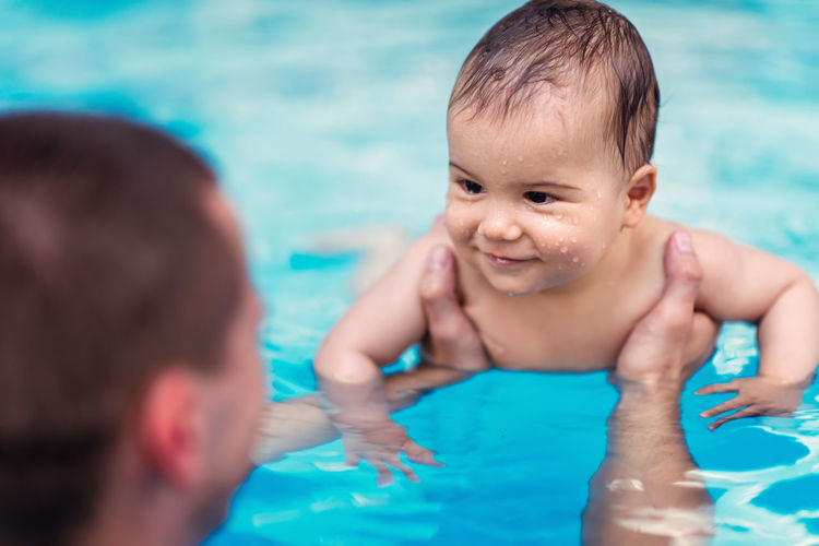 Smiling mother and son swimming in pool