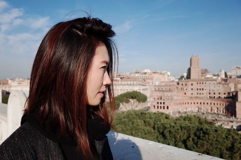 Close-up portrait of woman with cityscape against sky