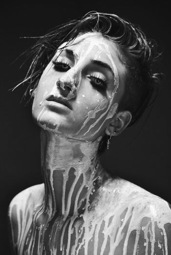 Portrait of topless woman with body paint against gray background