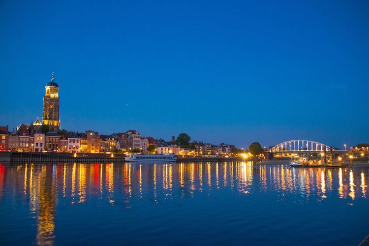Illuminated buildings by river at night