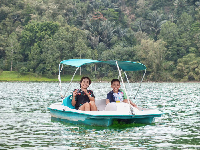 Portrait of mother and son in pedal boat on lake