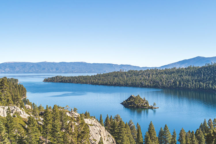 Scenic view of lake and mountains against clear blue sky
