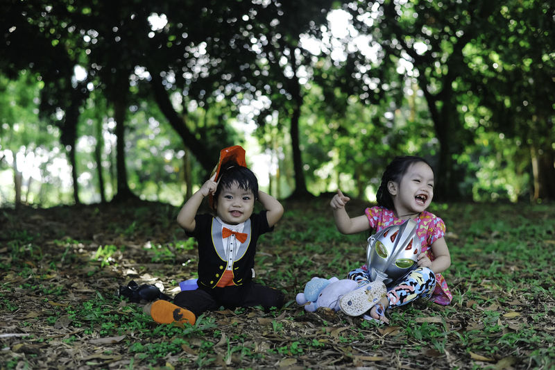Cute siblings sitting on grass at park