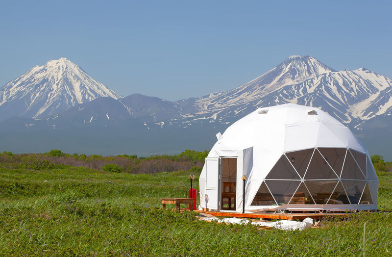 Glamping house in summer and volcano, rural landscape, tent houses in kamchatka peninsula. 