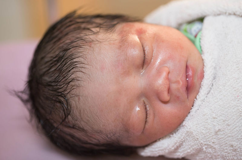 Close-up of cute newborn sleeping on bed at hospital