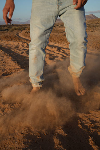 Low section of man standing on sand