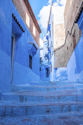 Narrow alley of blue town with staircase leading to residential structures on both side