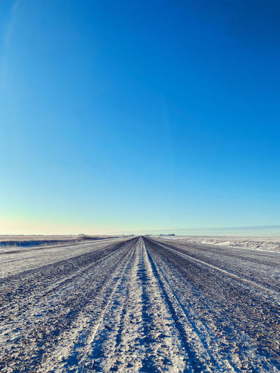 Road against clear blue sky during winter