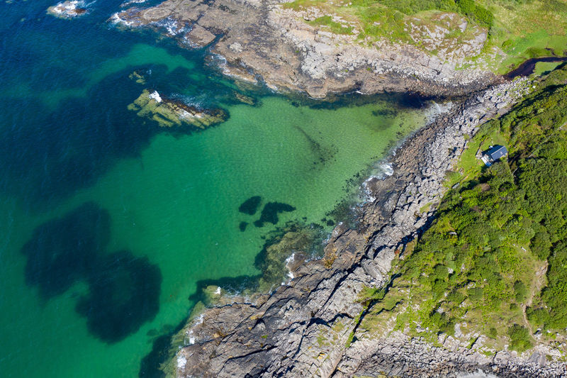Aerial shot of waves lapping up onto rocks in portuairk bay, scotland