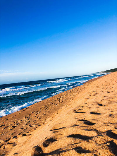 Scenic view of beach against clear blue sky