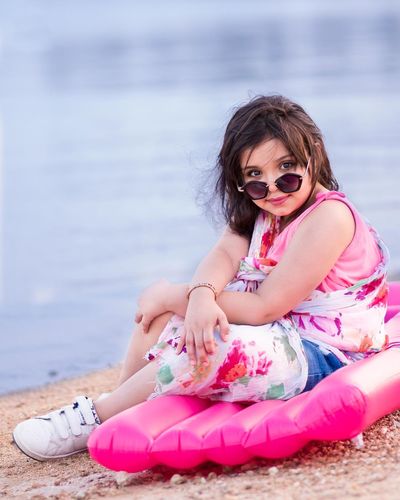 Portrait of girl in sunglasses sitting at beach
