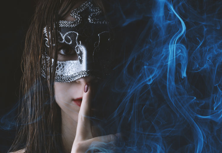 Portrait of woman wearing mask against black background