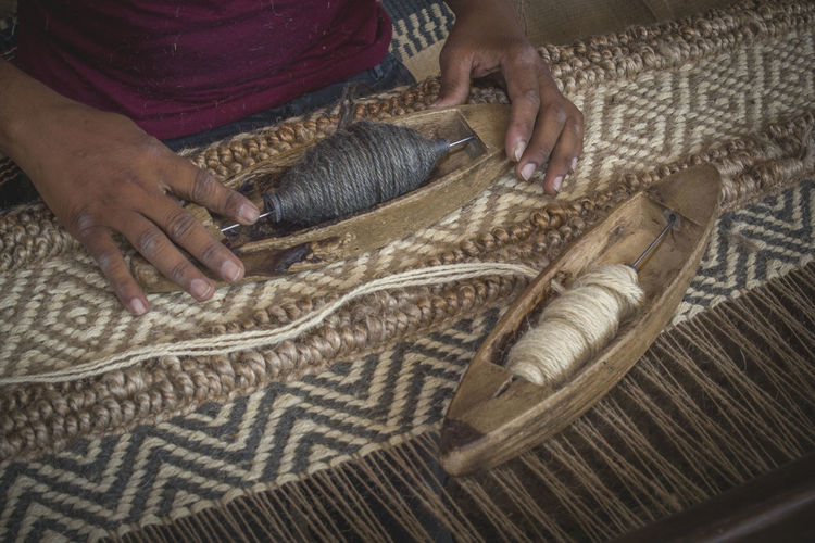Midsection of man weaving textile