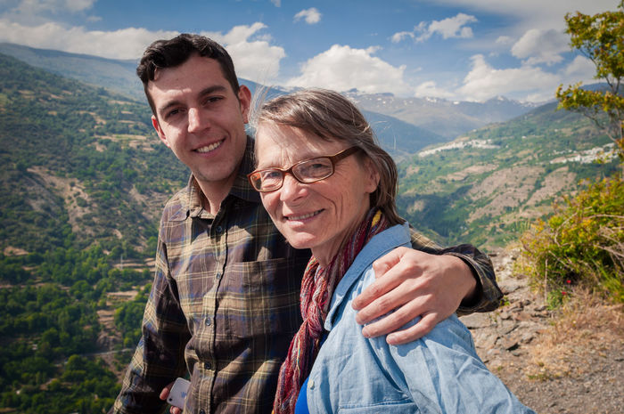 Portrait of young man with senior woman against mountains and sky