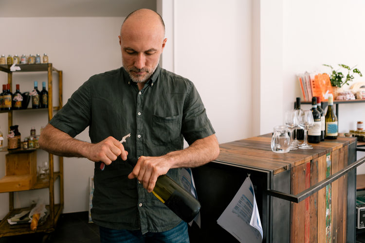 Sommelier opening a bottle of wine in his shop preparing a wine tasting