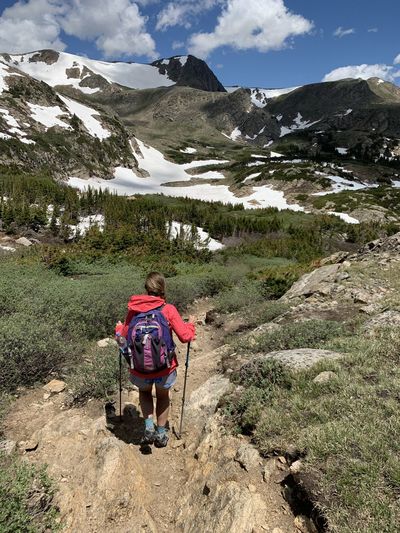 A woman hikes toward snowy mountains in the indian peaks wilderness in colorado 