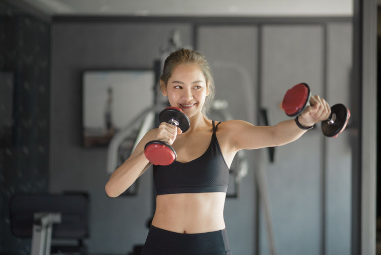 Young woman exercising with dumbbell in gym