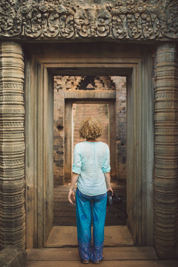 Rear view of woman standing at old ruin doorway