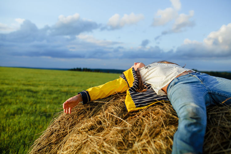 Woman lying on field against sky