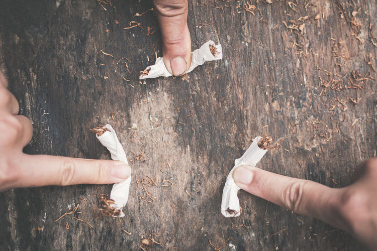 High angle view of hands holding cigarette