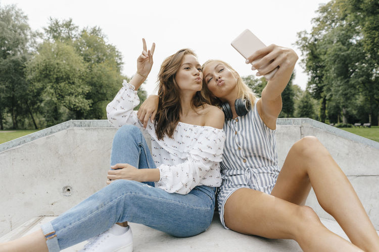 Two happy young women taking a selfie in a skatepark