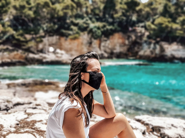Young woman wearing black mask at beach. summer, tourism, virus, corona, covid-19.