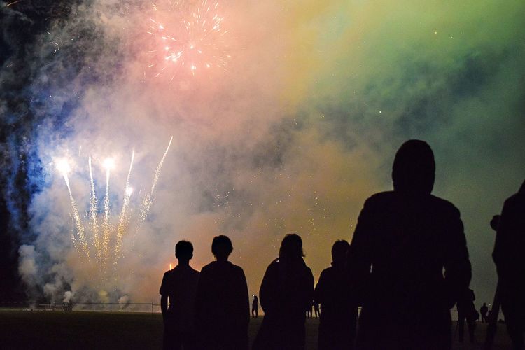 Low angle view of silhouette people against firework at night