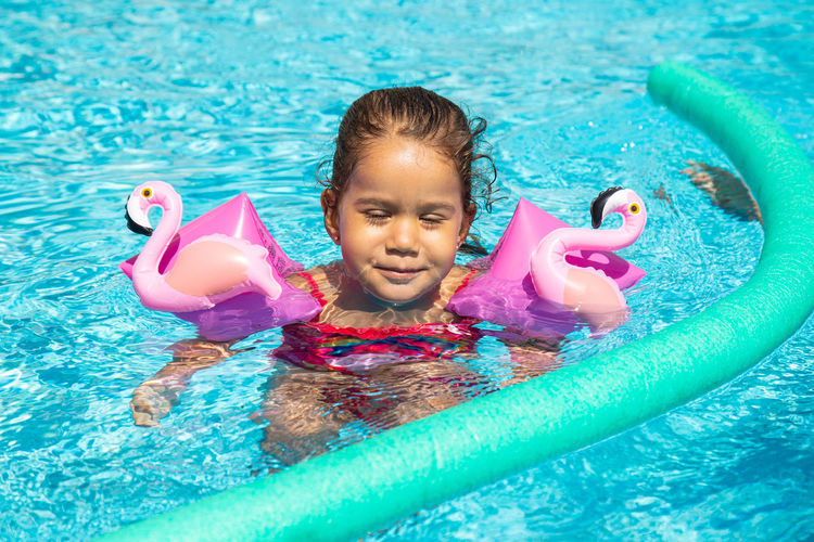 Little girl enjoying herself in the swimming pool with floats