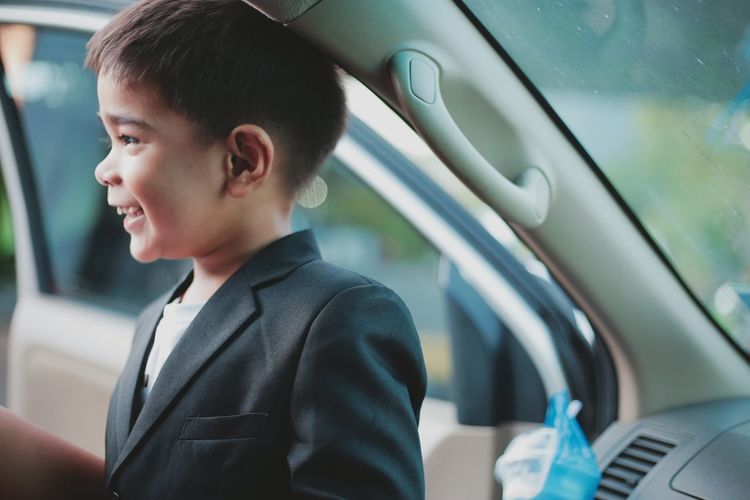 Side view of smiling boy in car