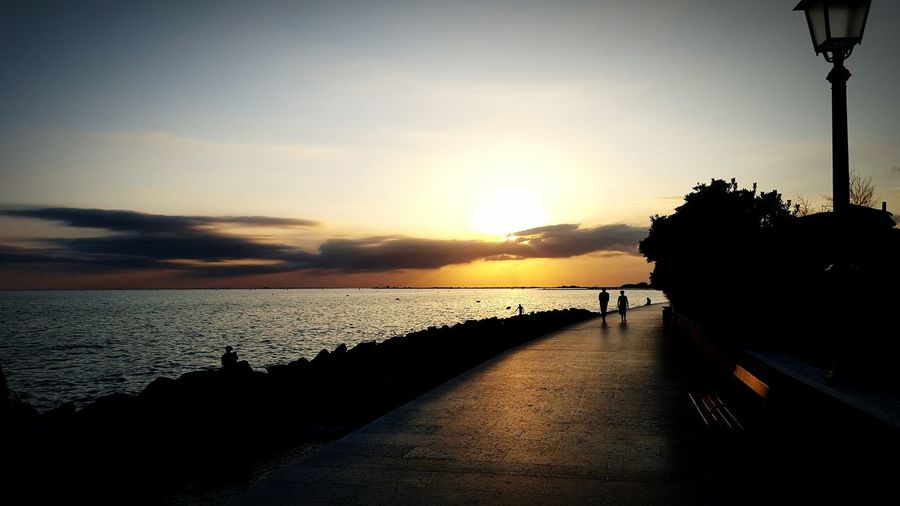 Scenic view of footpath and waterfront at sunset